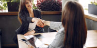 Two beautiful women working. Friends in a cafe. Businesswomen talking and working with a tablet