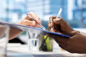Close up of man writing signature on contract after being hired by recruiter